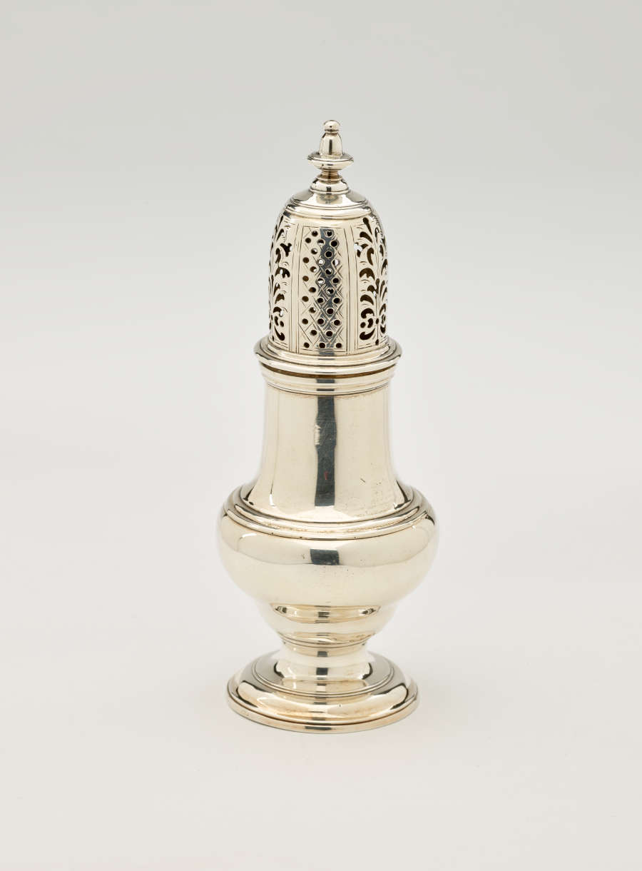  A silver vessel with a foot, rounded body that goes to a cylindrical top half, and the lid is perforated with small holes and floral cutouts.