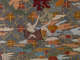 Intricate embroidery on a gray fabric depicting a figure in a brown robe reclining atop multicolored clouds above a grid of flowers, pointing up at a deep red Chinese character.