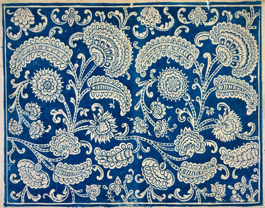 Repetitive wallpaper sample depicting a dense, ornate, bright blue and white pattern showcasing paisleys and intricate stylized floral motifs on a white base.