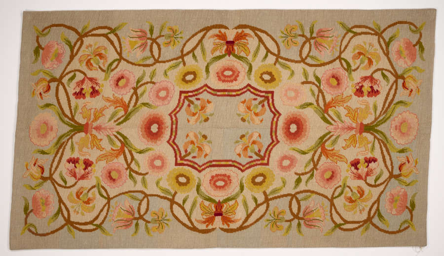 Floral design with scalloped rectangular center medallion. Vines with salmon-colored flowers twist around it. Palette includes tan, peach tones, green, and light blue.