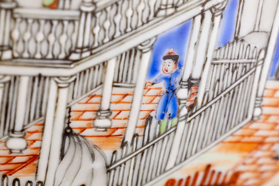 A close up of a painted ceramic depicting a figure dressed in blue ascending a decorative staircase with ornate railings, red brick floor, and a blue background.