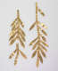Two gold branches with slender, delicate leaves arranged vertically next to each other. The left branch’s stem is partially disconnected at one end. 