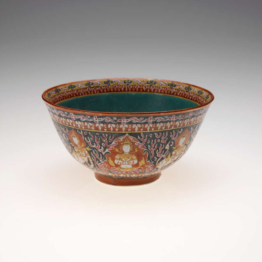 Bowl with a small base and wide, slightly flared mouth. Its turquoise interior’s rim features red and golden patterns. Its outside features sitting figurines against red, golden, and blue patterning.