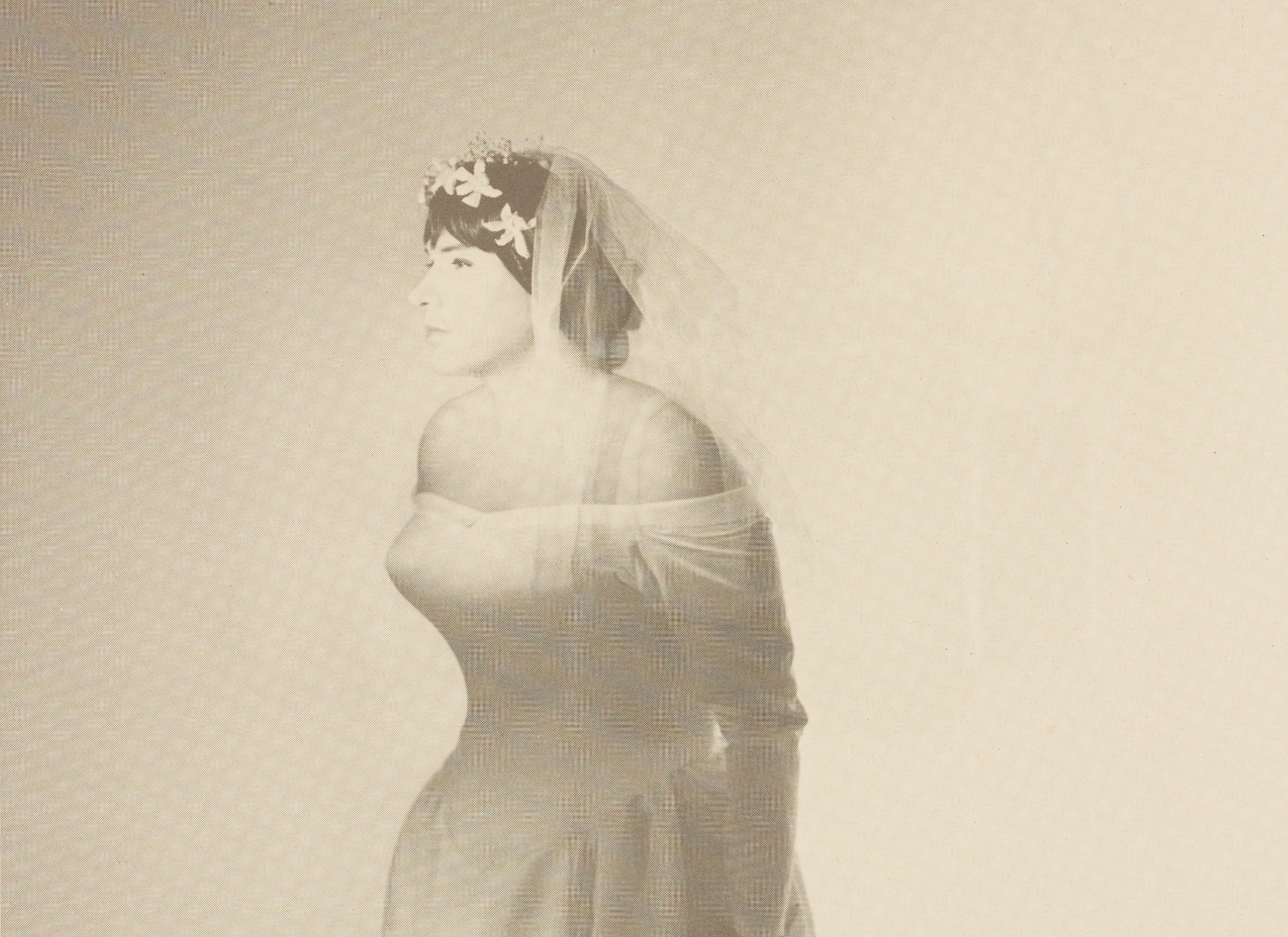 A single tone print of a newspaper page featuring a person in a strapless, long-sleeve, bridal gown and veil holding flowers in their left hand and staring out of the frame. The top of the page reads “The New York Times International Sunday, July 19, 1992" with the following headlines: “Vatican Condones Discrimination Against Homosexuals" and "Youth Works Held in Death of Son, 9”. The bottom of the pages reads “Saks Fifth Avenue bridal wear.”