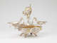 Elaborate silver double-oval-tray centerpiece with central winged-figurine holding up a gold garland with two cherubs, framed by swirling arms extending to two shallow dishes, all elevated on four legs.