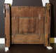 The back of a wooden panel with visible cracks, metal brackets, and reinforcement components, showing signs of wear and age. 