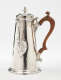 A silver chocolate pot with a spout, hinged lid, and fruitwood handle that is 90 degrees from the spout.
