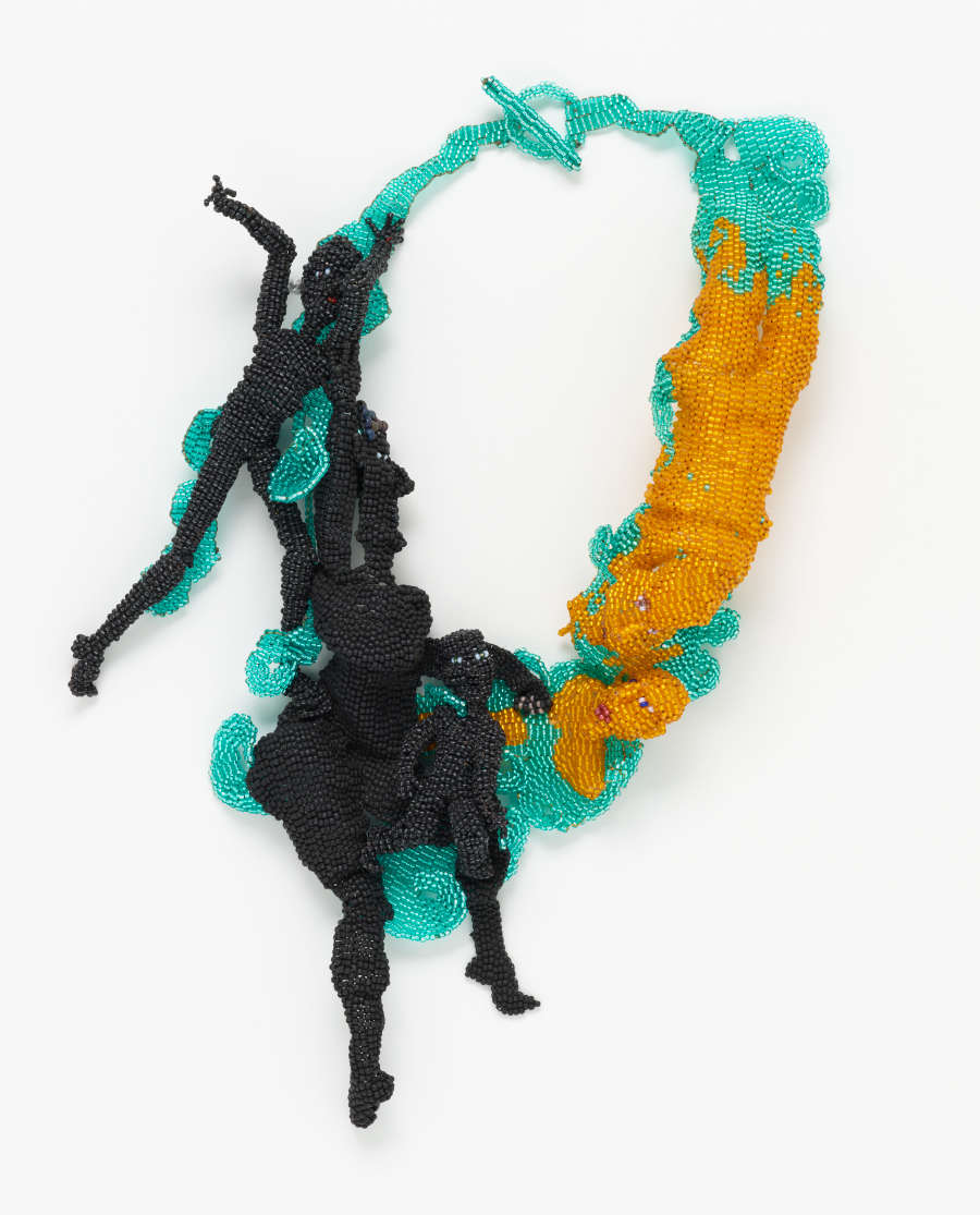 A necklace made of small, shiny beads featuring thin, dangling black figures on one side and wider, yellowish-gold figures on the other. Connecting them is a web of teal beads.  