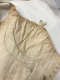 Close-up of slightly discolored cream fabric garment with delicate stitching, gathered neckline with small looped ribbon and small eyelets on the side. 