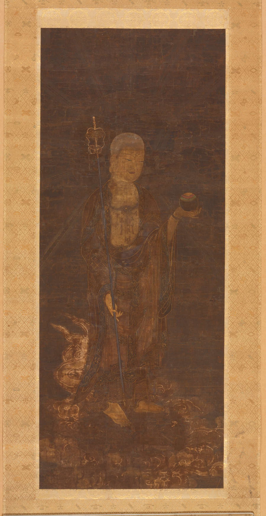 An ink painting in slight color and gold of the bodhisattva Jizō descending on clouds. Jizō carries a round wish-granting jewel in one hand and a staff in the other. 