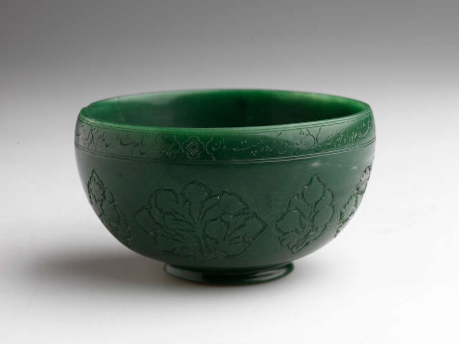 A rounded, green colored vessel with incised floral designs.