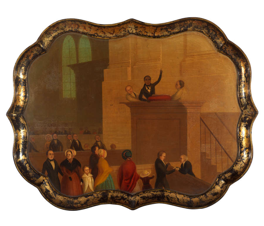 A tray with black and gold scalloped edges. The center image shows people inside a church. A Black figure stands, arm raised, between two white figures at the pulpit.
