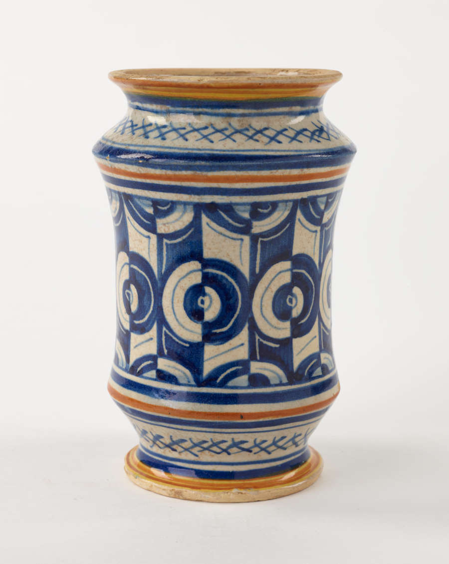 A jar with white, orange, and blue symmetrical decorations.