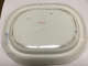 The underside of a white, oval-shaped porcelain dish with a slightly raised rim, with visible scuffs, discoloration, and a red identification number "35.195" at the center.