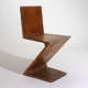 An angular wooden chair formed by four flat planes, creating a bold zigzag profile.