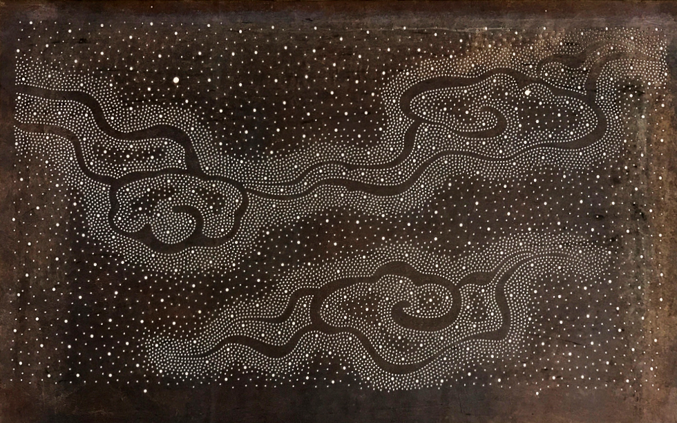 An intricate stencil of white dot patterns on dark brown background that form celestial motifs resembling wispy clouds floating across a starry night sky. 