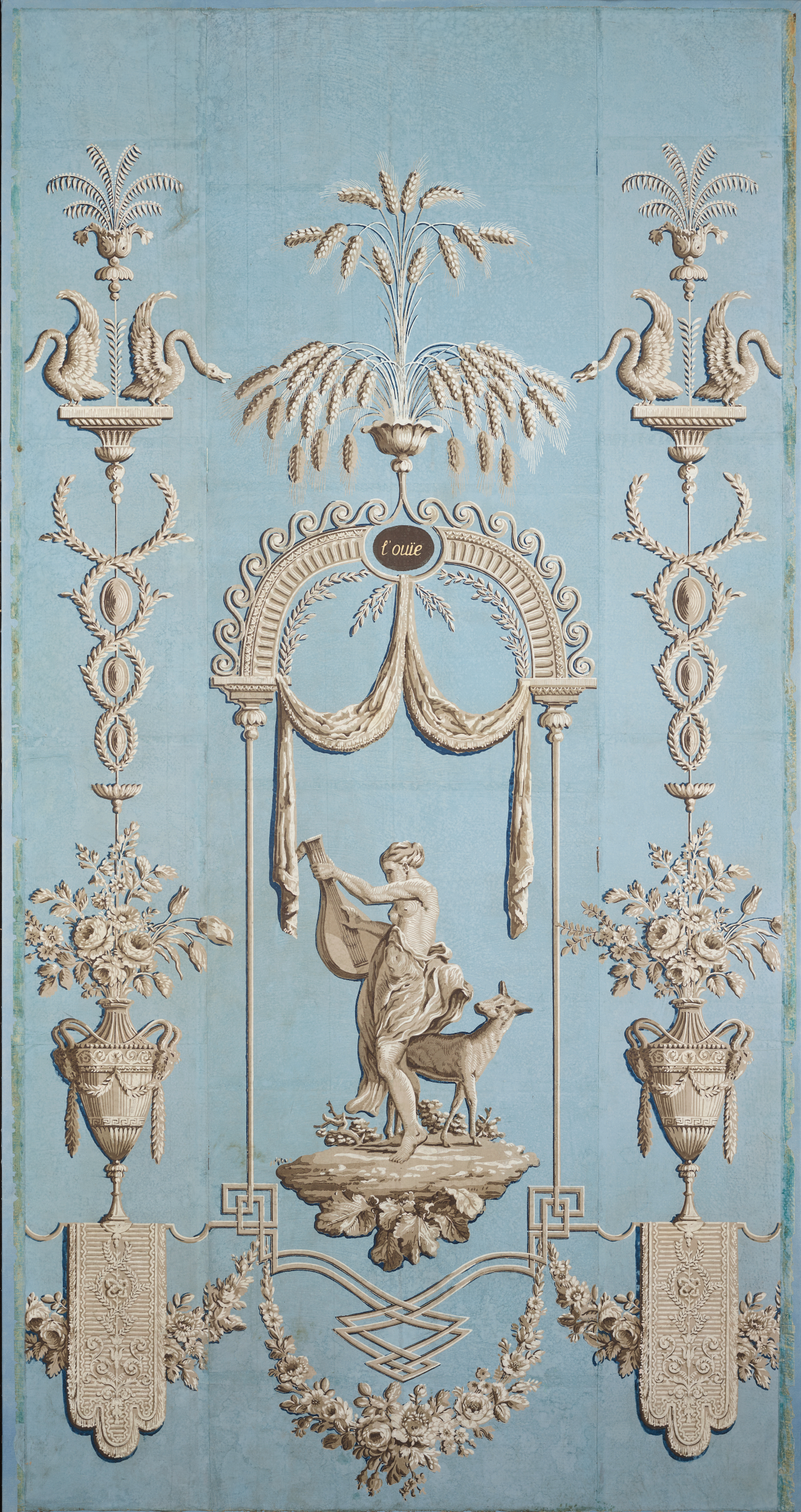 Narrow panel of vintage wallpaper featuring a central figure with an animal in a garden scene, surrounded by botanical motifs in ivory. The design is against a light sky-blue backdrop.