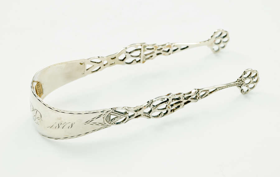 Silver sugar tongs with decorative cutouts.