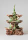 An elaborate, sculptural, three-tiered dish. Colored in brown, green, and cream with floral decorations as well as sculpted fish decorations.