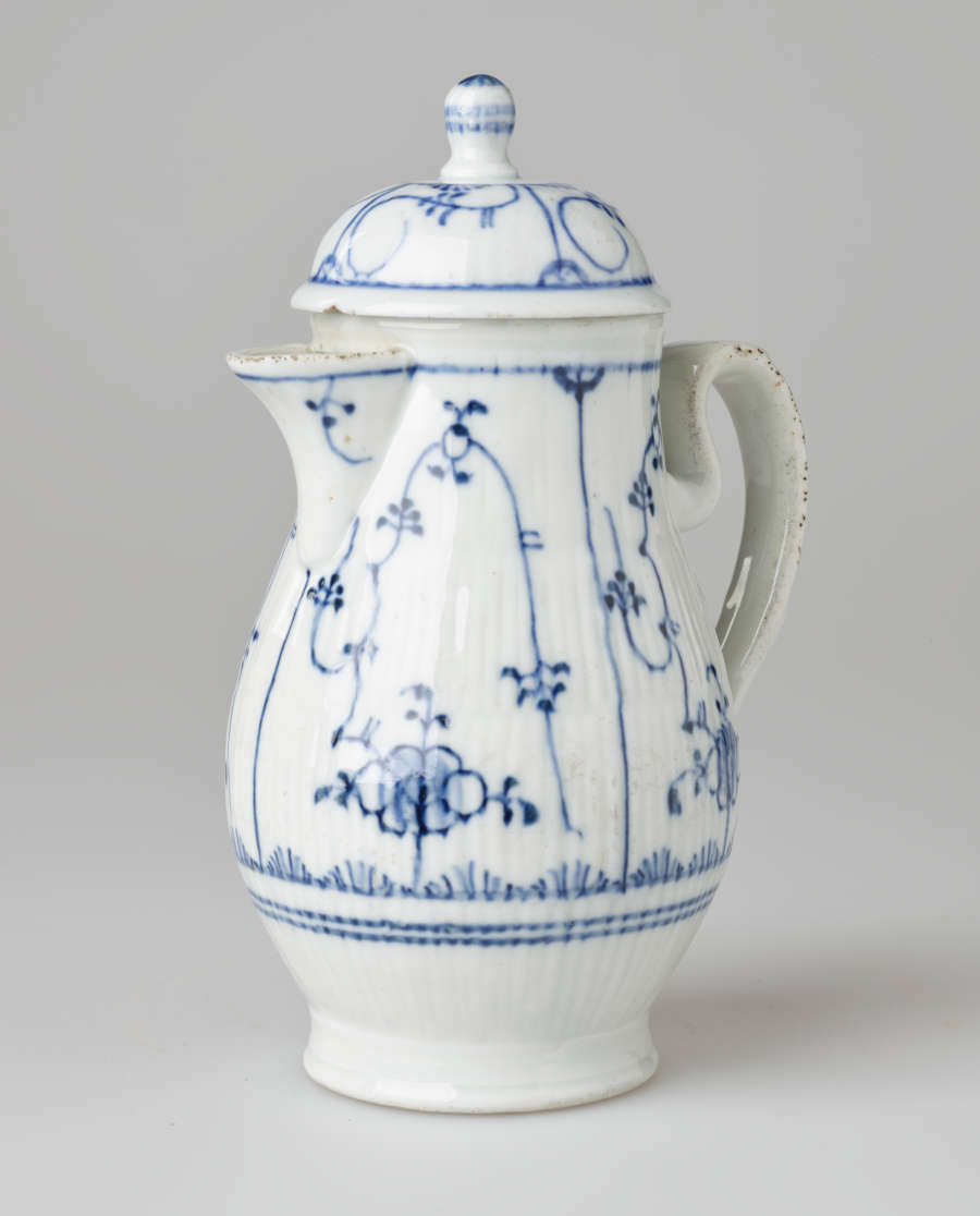 A white chocolate pot with delicate blue decorations with ribbed body, spout, handle, and foot.