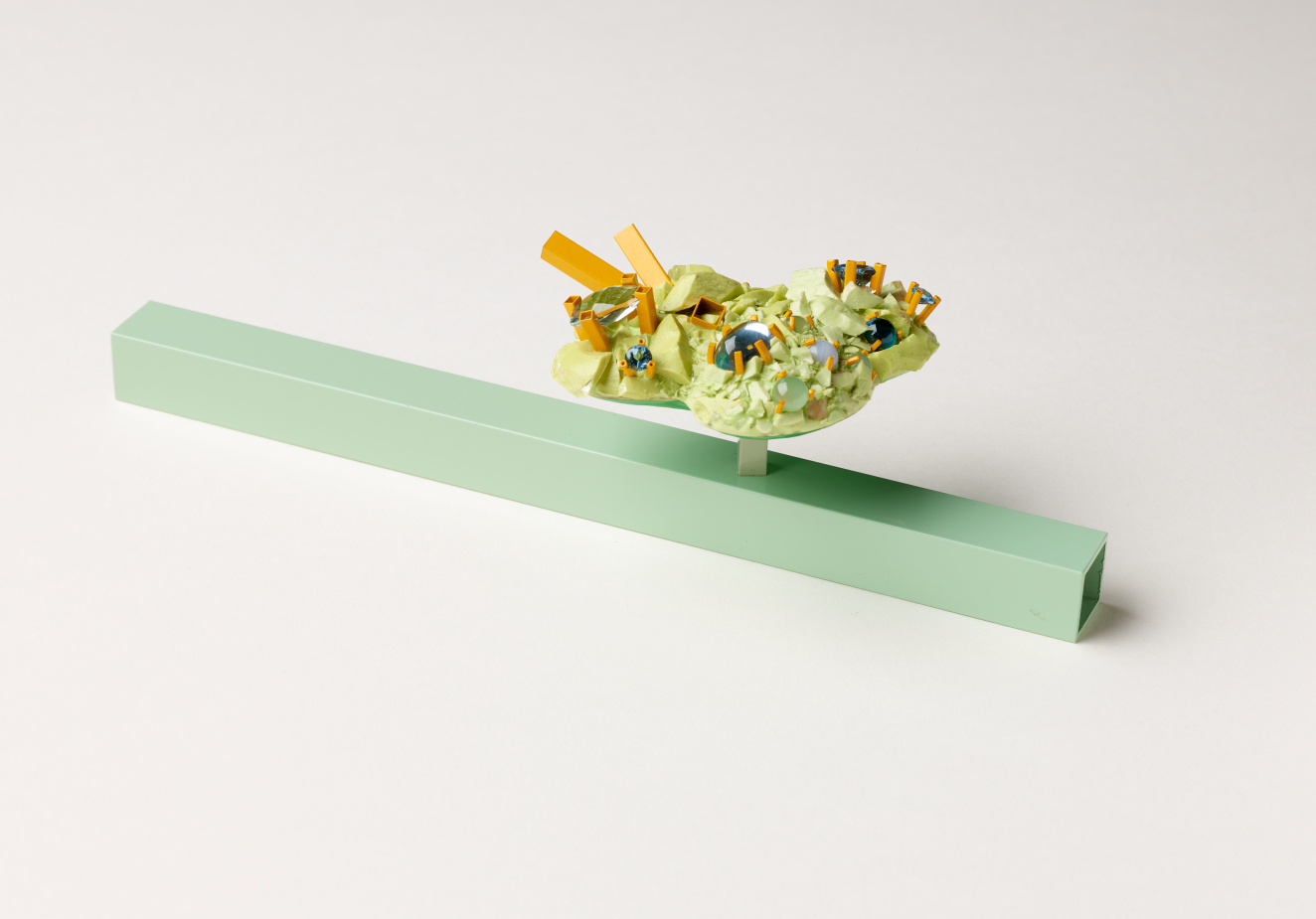 A horizontal mint-green beam and raised yellow cluster adorned with colorful gems and protruding orange rods.
