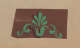 Decorative brown panel on a neutral backdrop featuring a green floral design with a fan-shaped center and flowing curves on either side.