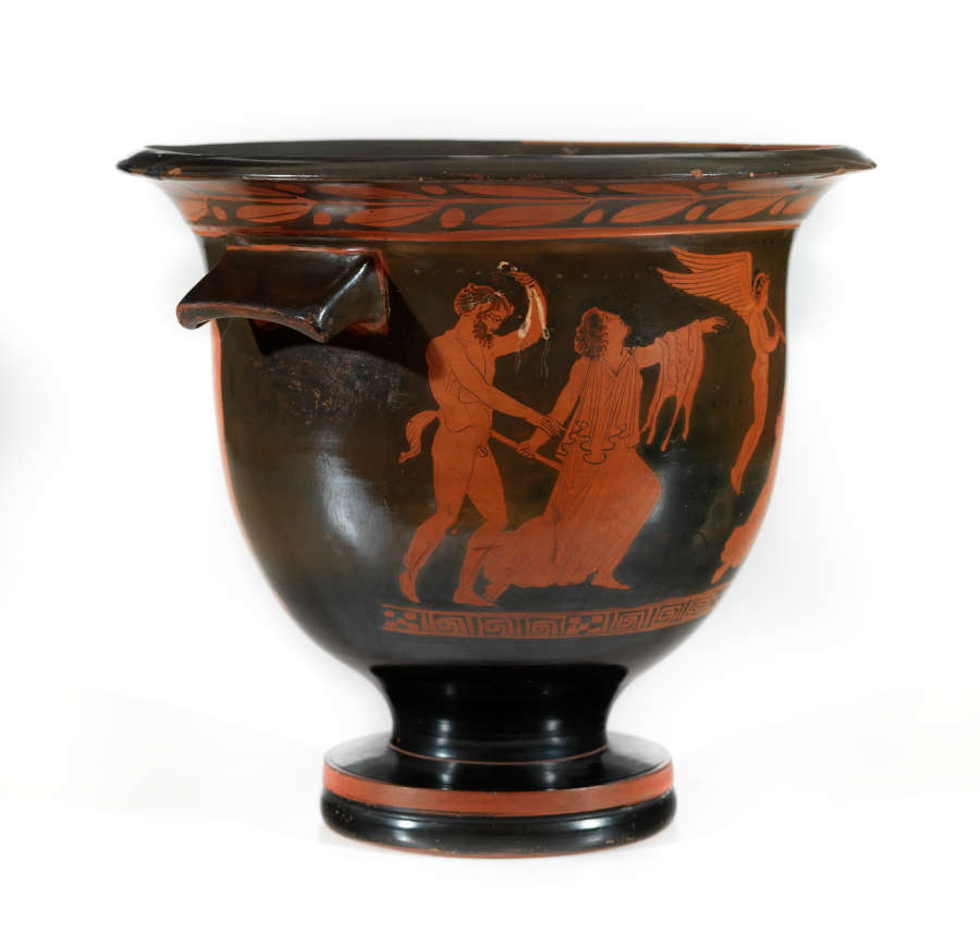 Stout black bowl with a wide striped foot and flared patterned mouth. Visible is one sloping handle, and the terracotta illustrations of satyrs troubling humans on the right half.