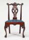 An intricately carved wooden chair with an open back and a blue upholstered seat supported by clawed feet.