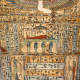 Close-up of a coffin panel with hieroglyphic inscriptions and painted figures in colorful robes bordered by a row of small decorative jars along the top.