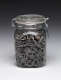 A glass jar tightly packed with gray and white striped sunflower seeds, sealed with a hinged metal clasp and a glass lid.