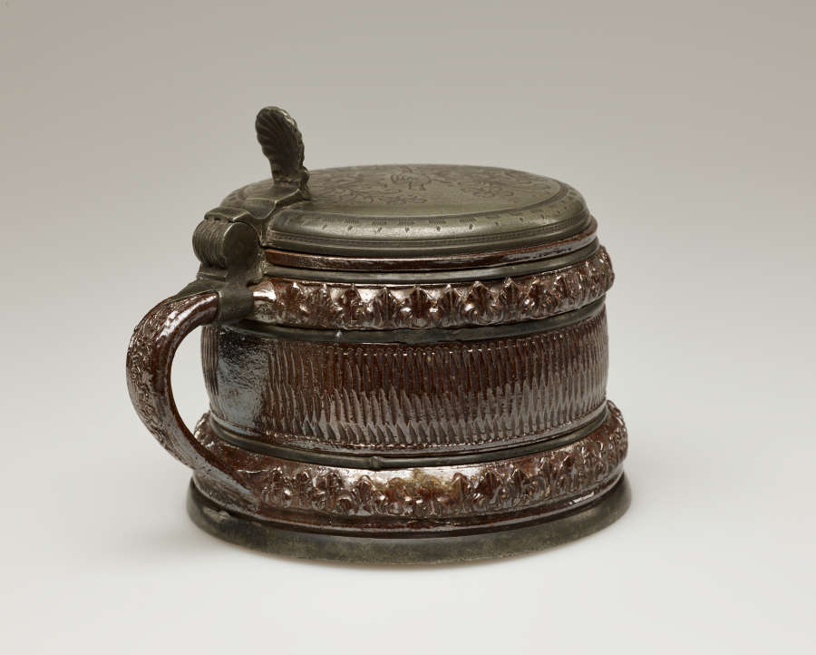 A brown and tan mug with a silver, scalloped rim.