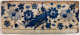 A horizontally long rectangular tile fragment. The top is worn, brown and off-white with indigo designs of a bird against a symmetrically arranged floral pattern. 