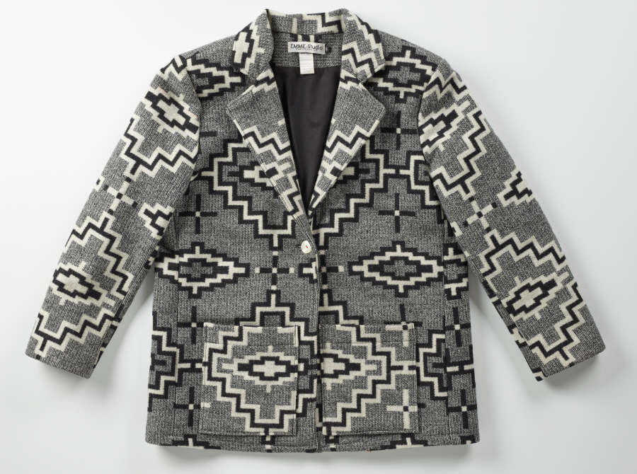 Gray tweed buttoned blazer with black and white geometric patterns throughout. The blazer has two pockets on the lower center and a single white button in the middle. 