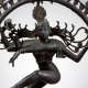 Close up of the Hindu god Shiva, highlighting his serene face, flowing hair, and multiple arms. One arm holds a symbolic object, while another gestures in front of him.