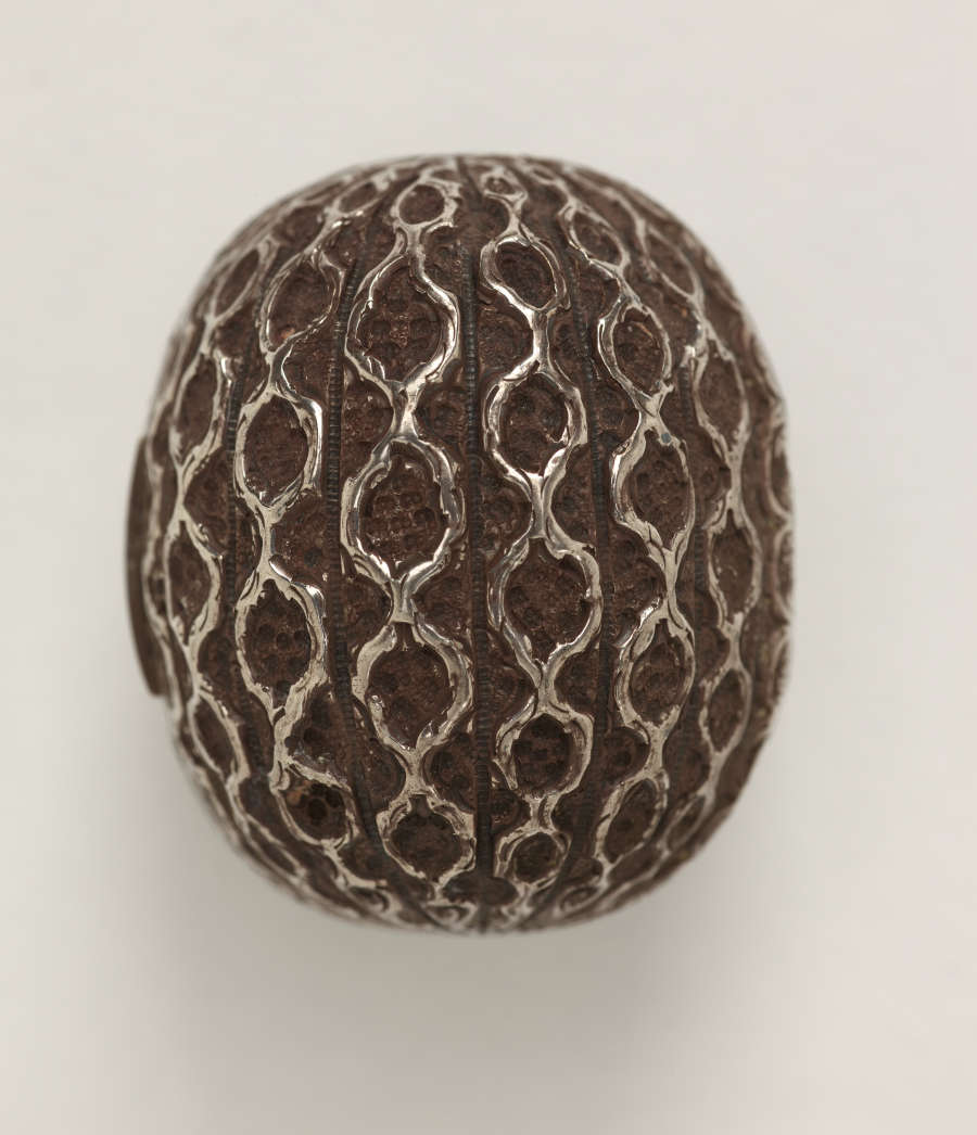 A silver nutmeg grater that is abstractly shaped like a nutmeg.