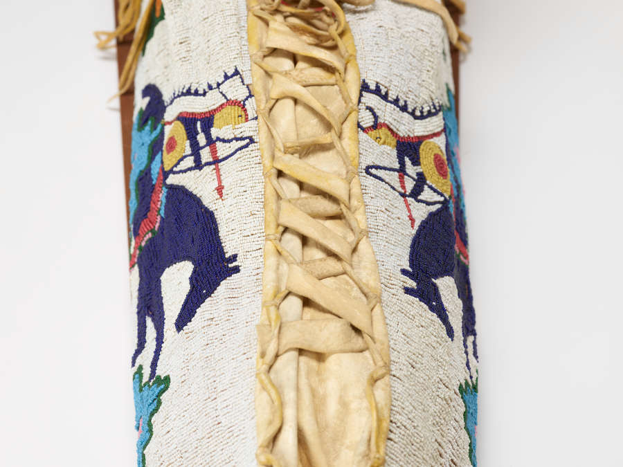 Detail of a beaded object with a panel of leather lacing running top to bottom.