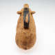 Angled back-view of a terracotta container in the form of a seated pig. Along its back is a chipped long black painted handle with a narrow-connected mouth.