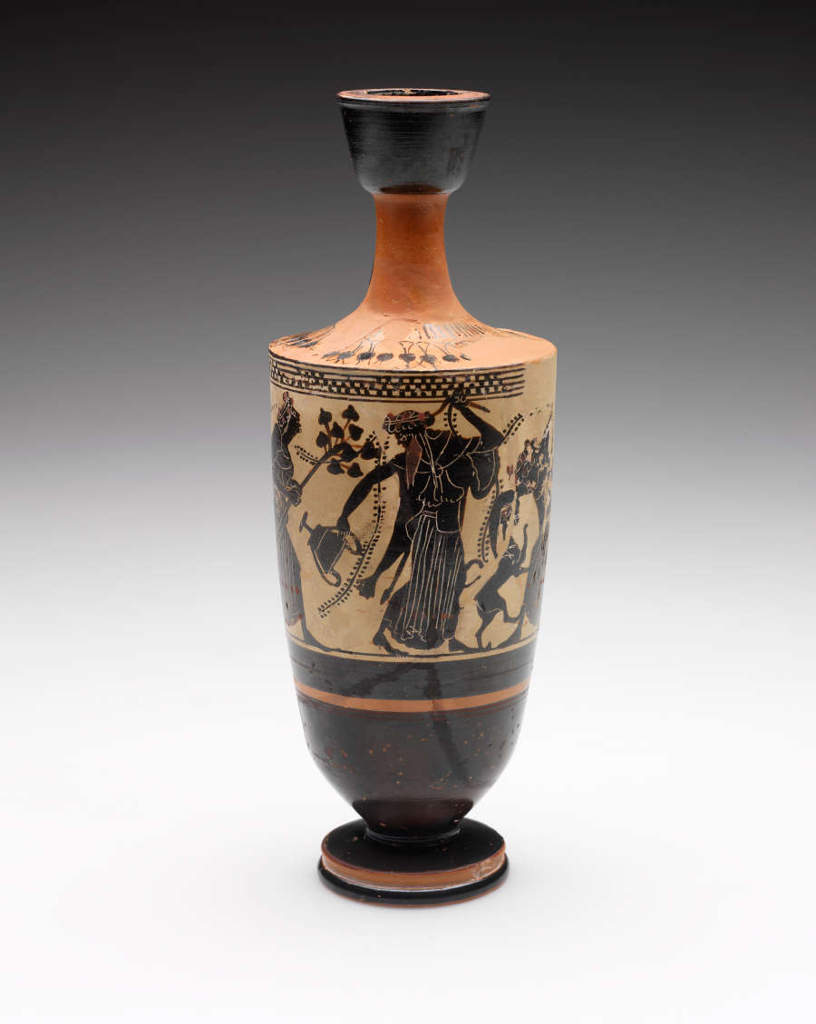 Tall vase with a slender neck. Its tan-orange surface is decorated with black illustrations of a band of robed humans and animals, as well as stripe patterns. 