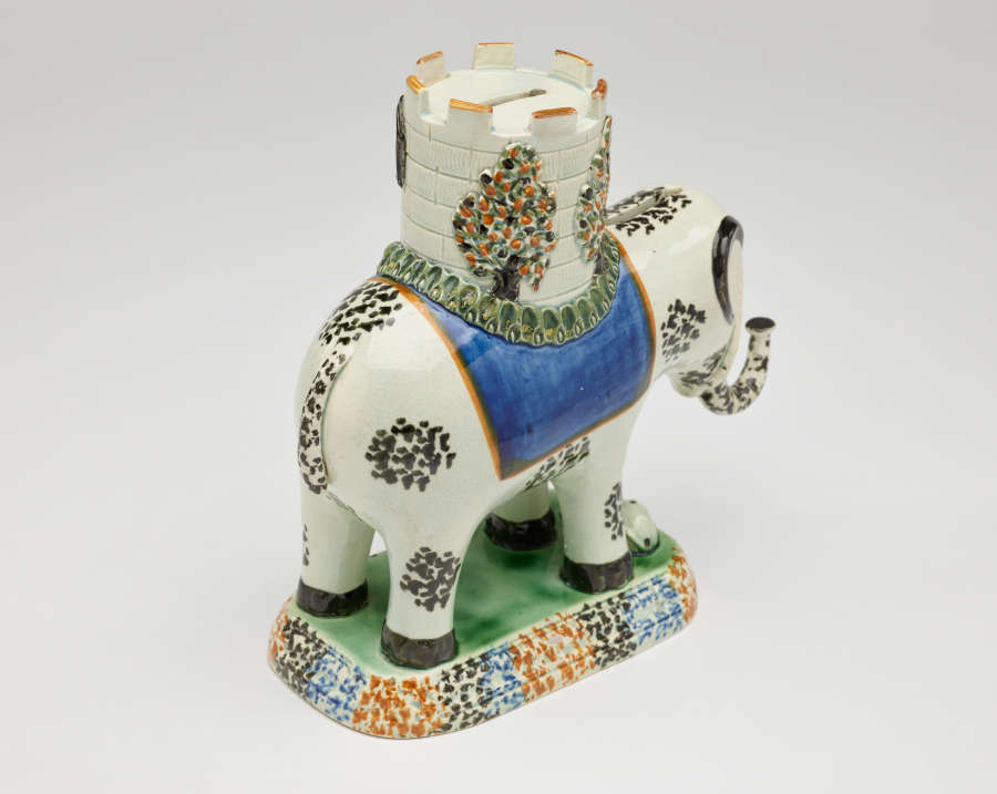  A sculpture in the shape of an elephant with a castle on its back. The decorations are white, blue, green, and yellow.
