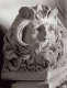 A close up of a marble coffin corner, featuring a bearded man with curled locks, looking upwards with a serious expression. 