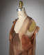 A profile view of a sheer sleeveless top, constructed of layers of sheer brown fabric draped on a dress form.