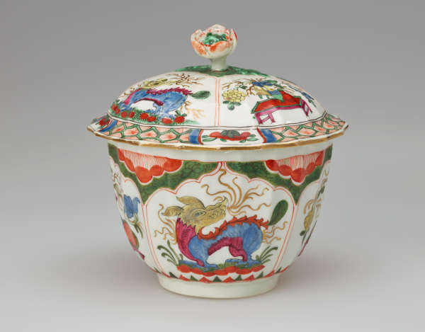  A white bowl with lid and finial with green, red, blue, pink, yellow and gilded decorations. The finial is a sculptural flower white, red and green.