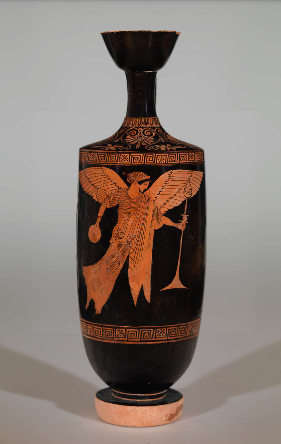 Vessel with an elongated, flared neck. Black background has an orange design with a winged figure holding a trumpet in one hand and a vessel in the other.