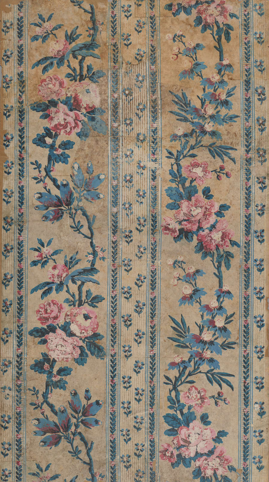Panel of vintage fabric wallpaper featuring vertically aligned, faded pink and blue garlands alongside patterned columns of small floral motifs. The design is set on a mottled beige background.