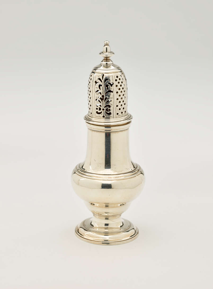  A silver vessel with a foot, rounded body that goes to a cylindrical top half, and the lid is perforated with small holes and floral cutouts.