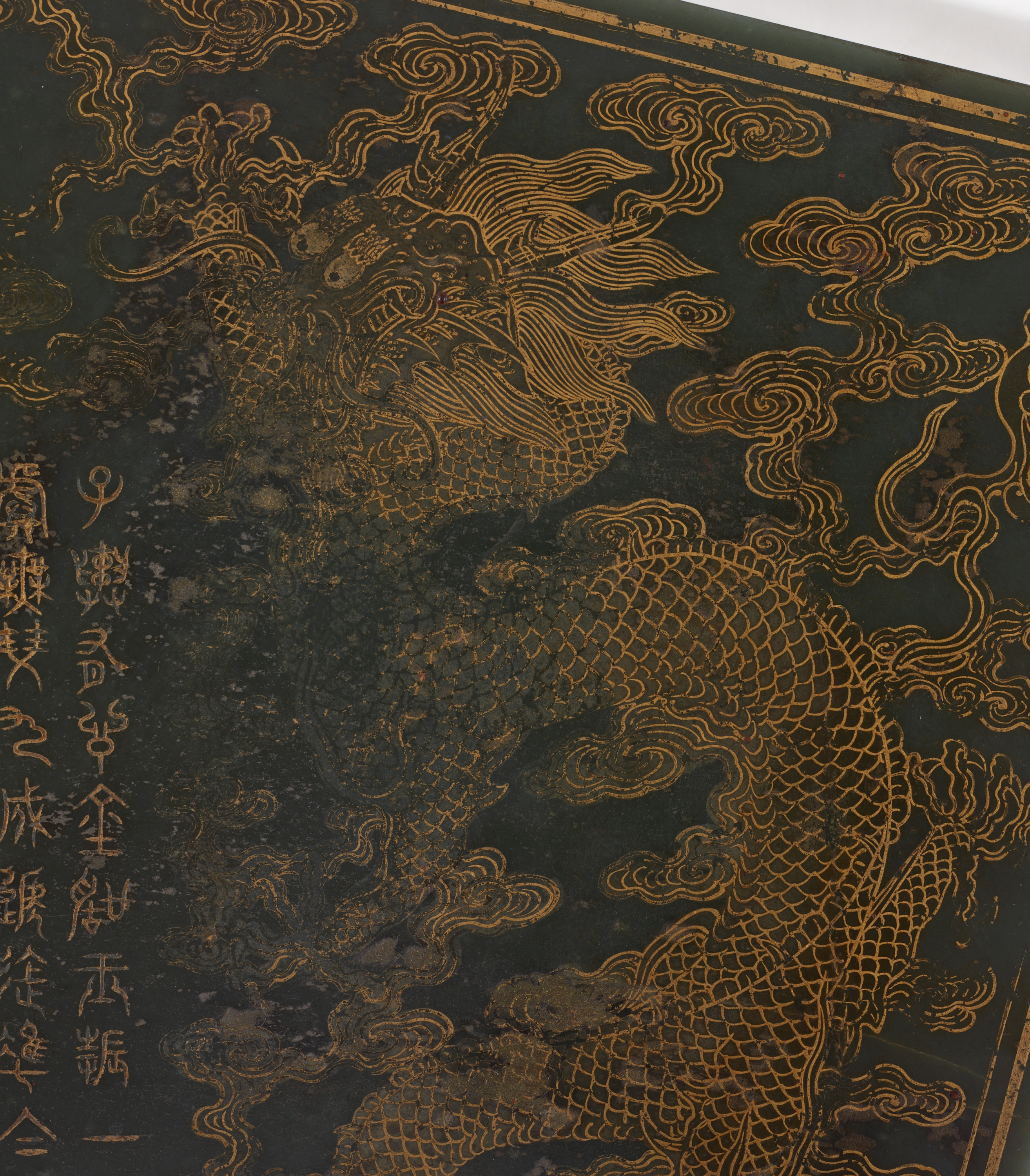 An intricately engraved instrument case with dragon and cloud motifs with visible signs of age and wear.
