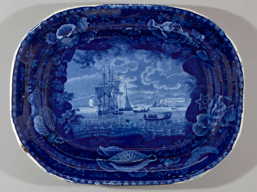 A deep blue ceramic platter with a central illustration of a large ship, framed by a border of seashells, coral, and marine motifs.