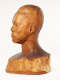 Profile view of a glossy wooden bust depicting the head of a  male figure. He has a stern expression and an intense gaze. The wood features long vertical cracks.