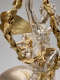 The backside of a silver cherub with curly hair, gold wings, and robes in the background of a larger silver-robed figure with gold wings holding a garland in the foreground. 