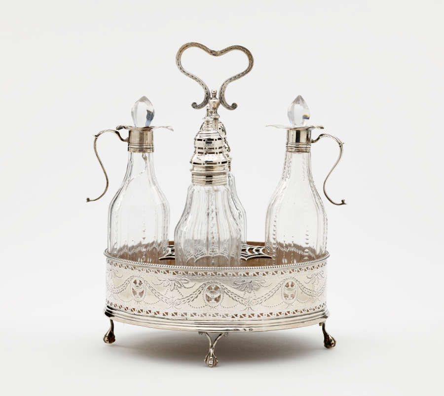 A silver container with small feet and a curved, open handle on top. Inside are several glass vessels with silver mounts.